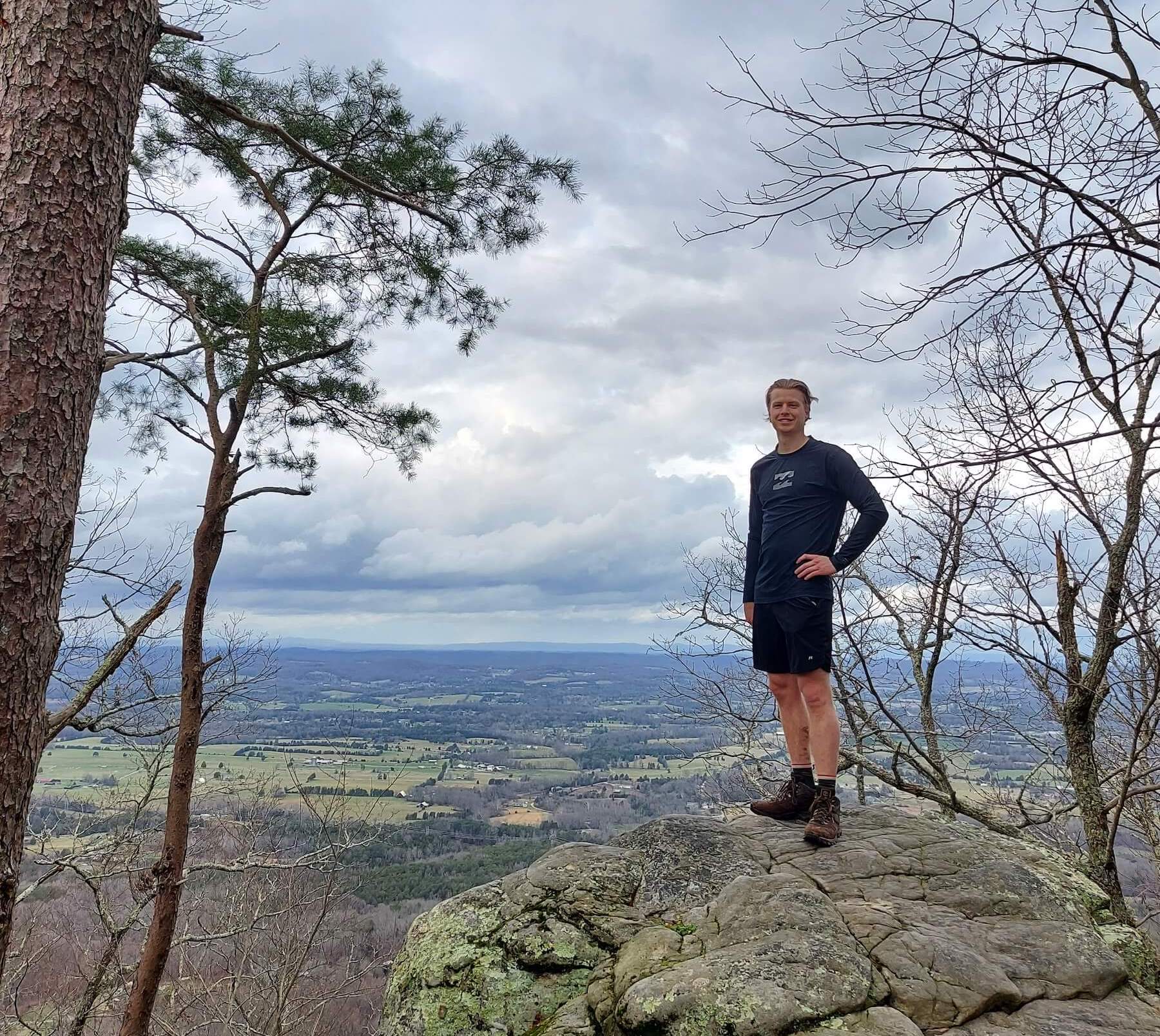 A man posing on a rock overlook